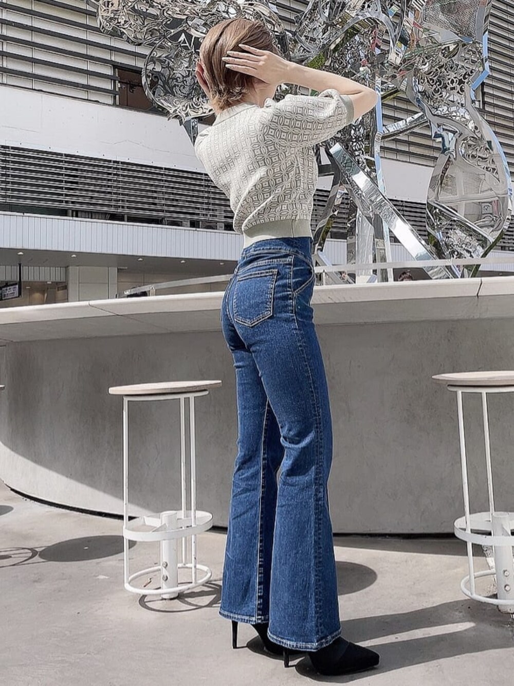 ブルー系のデニムパンツ、ブラック系のブーツ、グリーン系のニット/セーターを着用したレディースの春コーディネートの1枚目の写真