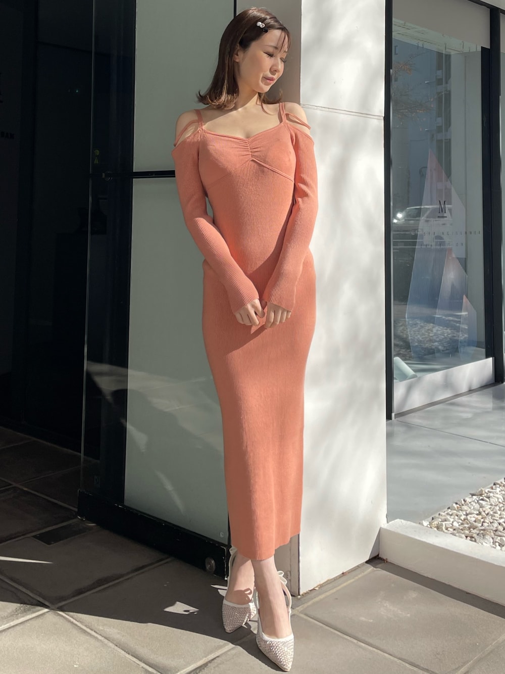 オレンジ系のワンピース、ホワイト系のパンプスを着用したレディースの冬コーディネートの1枚目の写真