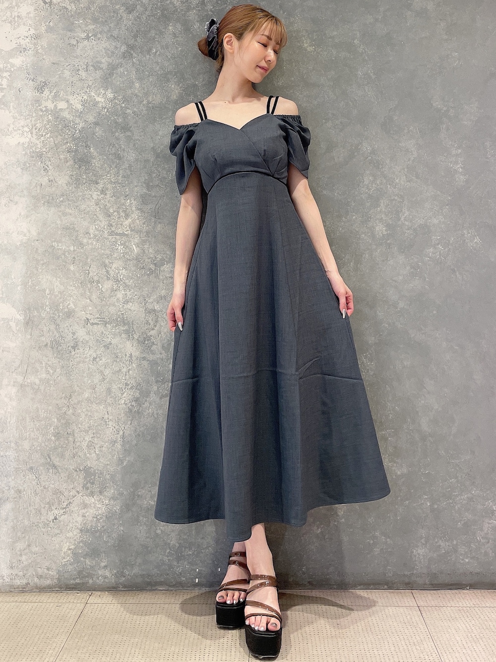 グレー系のワンピース、ブラック系のサンダル、グレー系のシュシュを着用したレディースの夏コーディネートの1枚目の写真