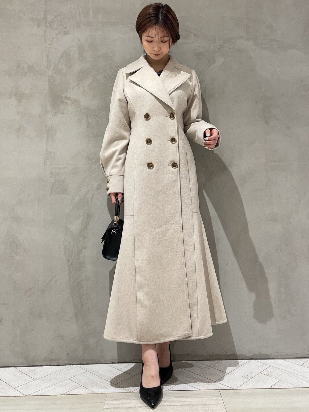 ベージュ系のその他アウター、グレー系のワンピース、ブラック系のハンドバッグを着用したレディースの冬コーディネートの1枚目の写真