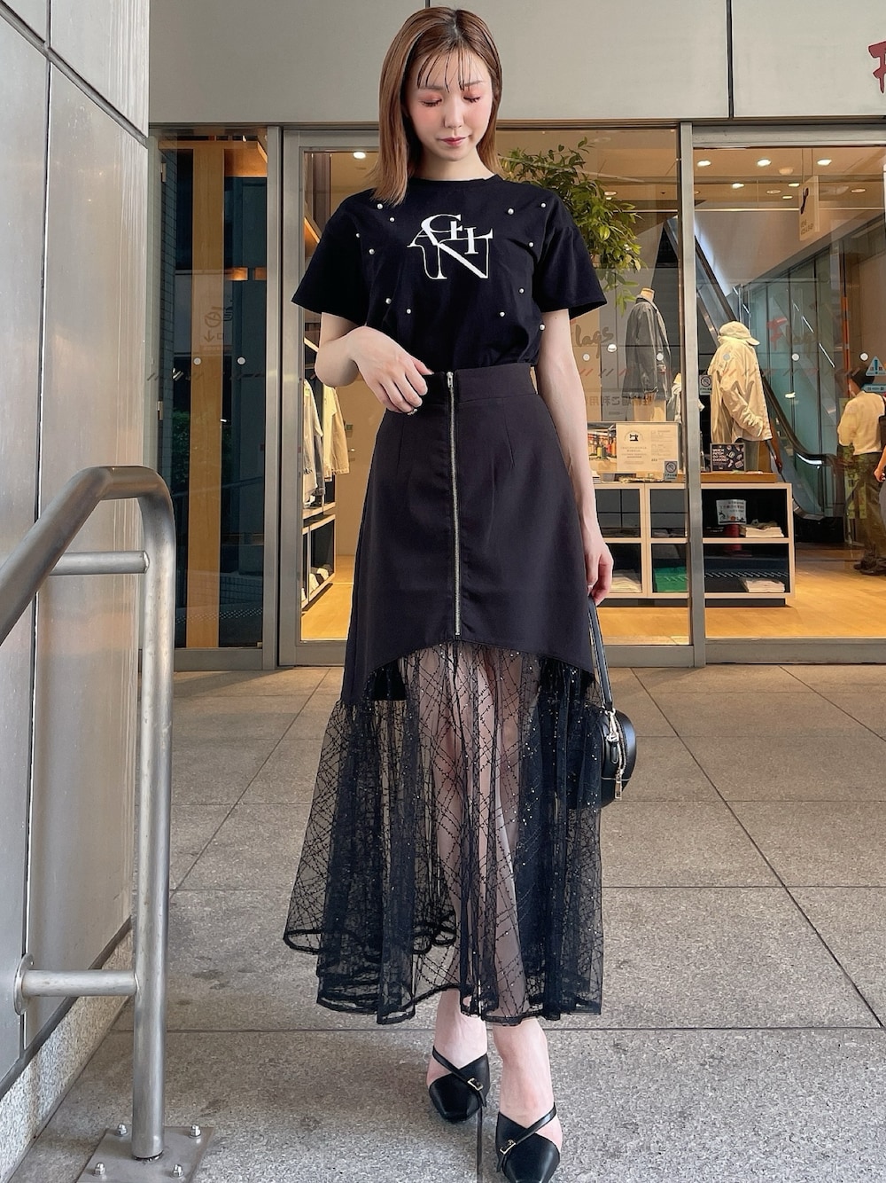 ブラック系のスリッポン、ブラック系のTシャツ/カットソー、ブラック系のスカートを着用したレディースの夏コーディネートの1枚目の写真