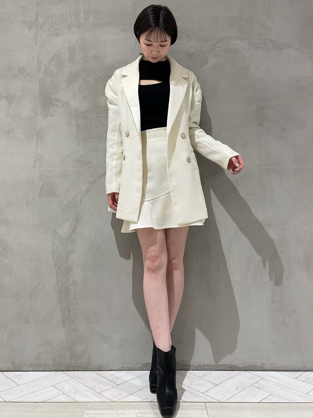 ホワイト系のテーラードジャケット、ホワイト系のスカート、ブラック系のニット/セーターを着用したレディースの冬コーディネートの1枚目の写真