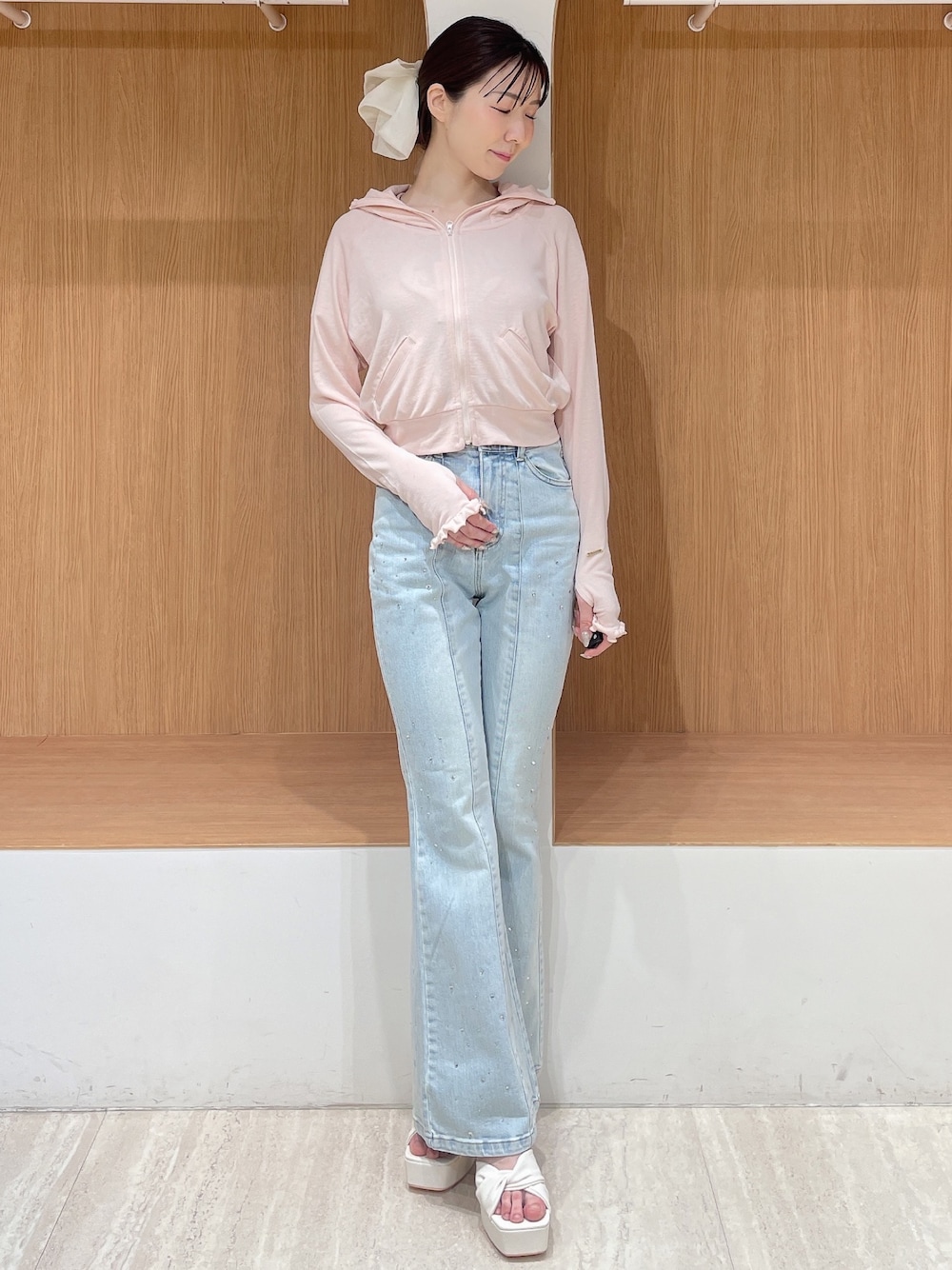 ピンク系のパーカー、ブルー系のデニムパンツ、ホワイト系のサンダルを着用したレディースの春コーディネートの1枚目の写真