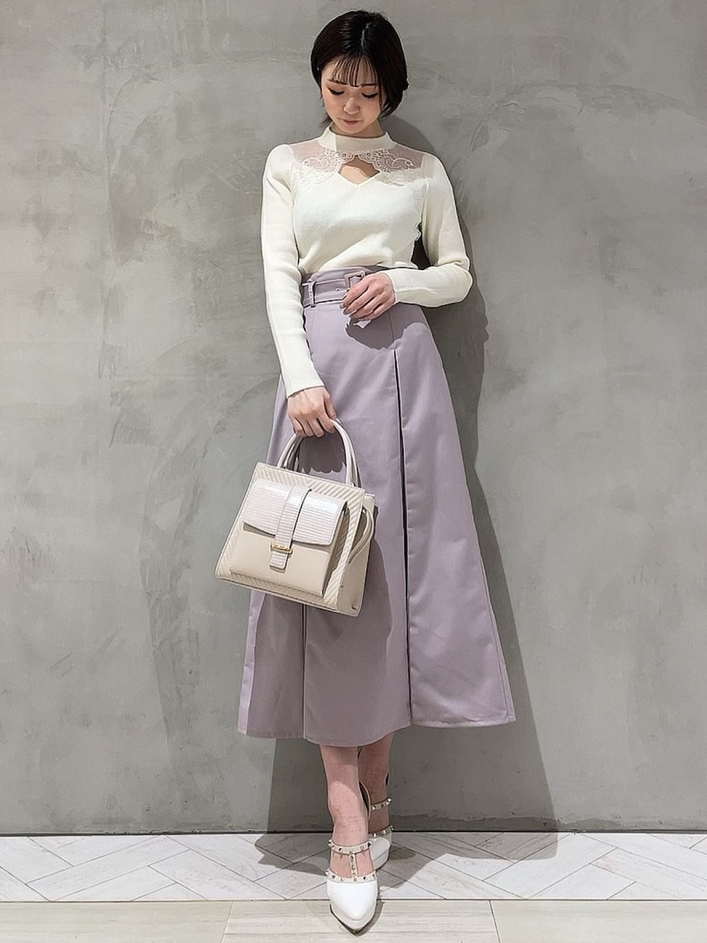ホワイト系のニット/セーター、パープル系のスカート、ホワイト系のハンドバッグを着用したレディースの冬コーディネートの1枚目の写真