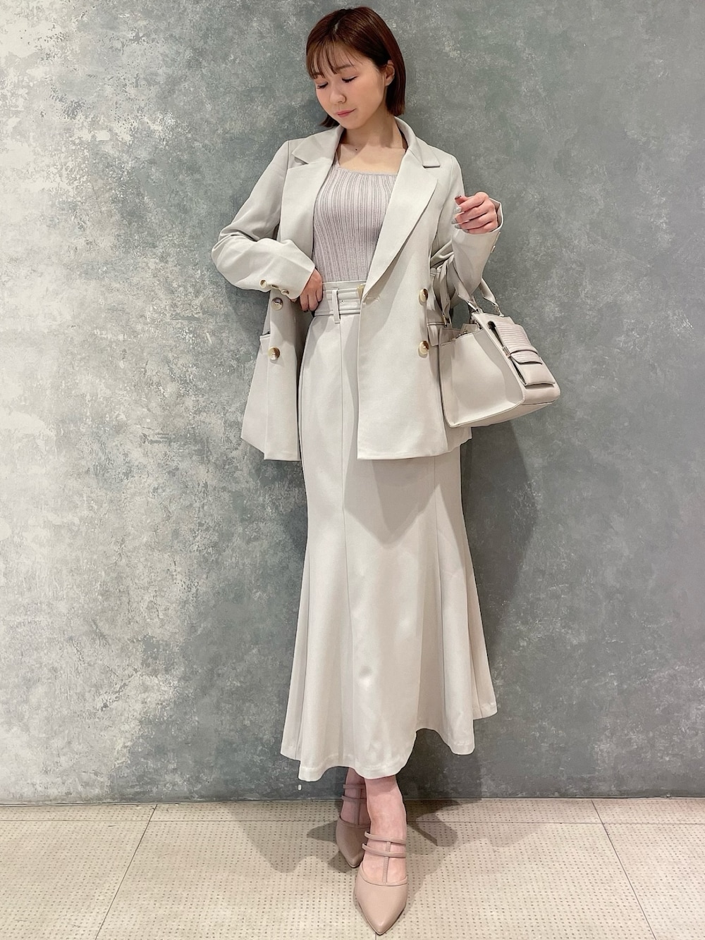 ホワイト系のテーラードジャケット、ホワイト系のスカート、ピンク系のパンプスを着用したレディースの春コーディネートの1枚目の写真