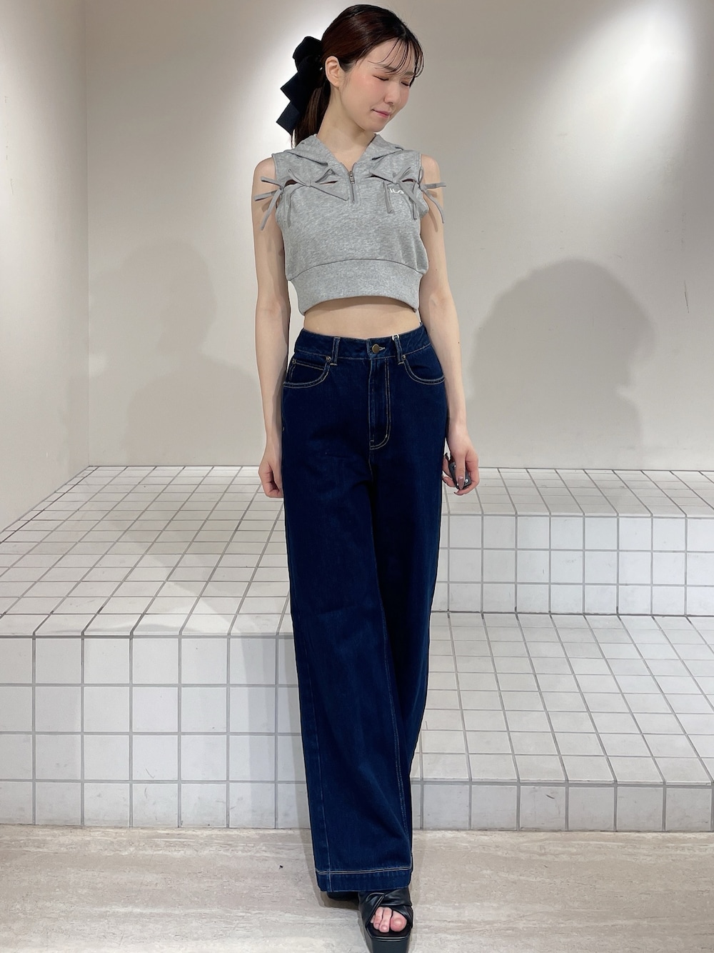 グレー系のパーカー、ブルー系のデニムパンツ、ブラック系のサンダルを着用したレディースの春コーディネートの1枚目の写真