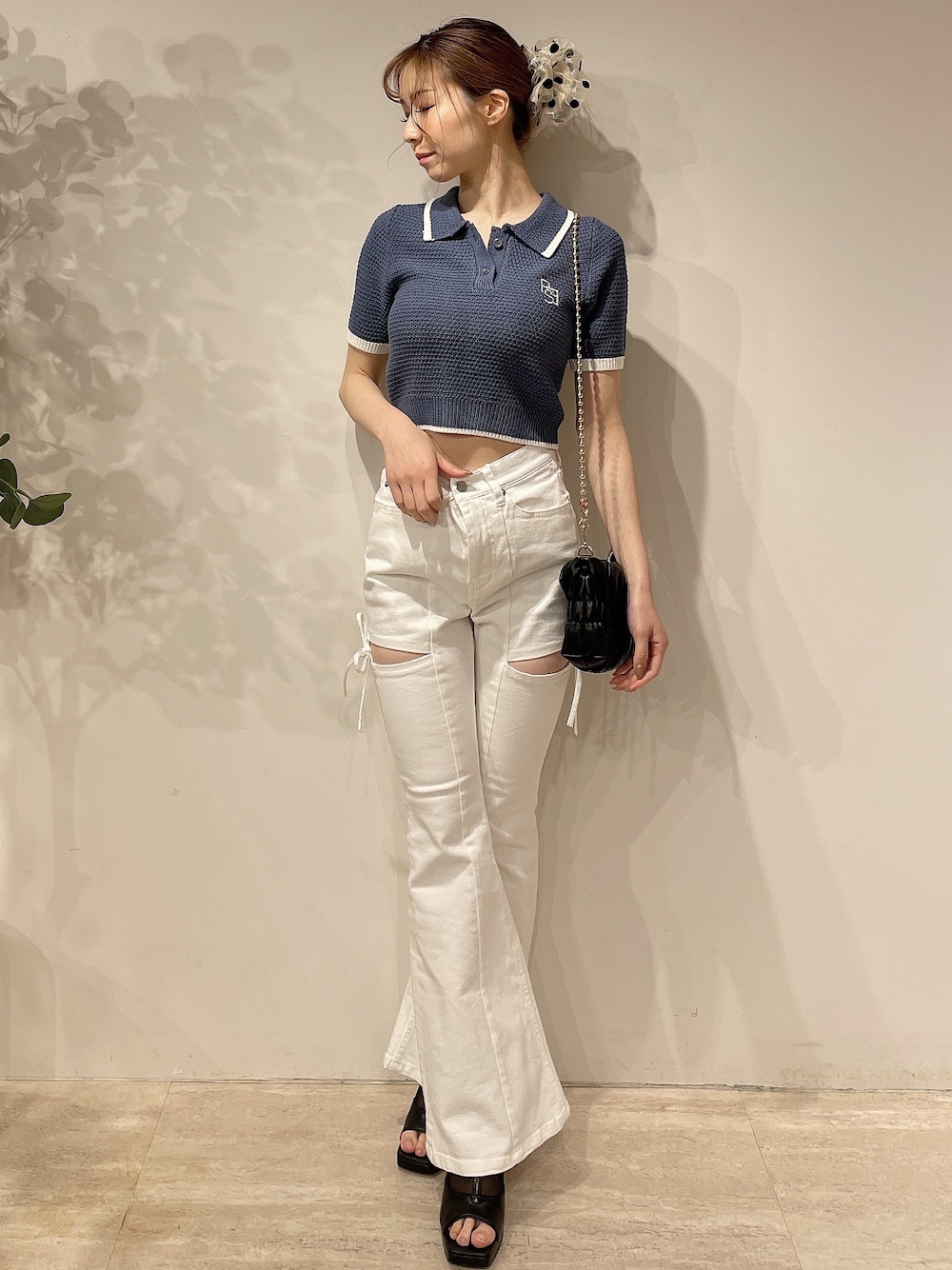 ブルー系のニット/セーター、ホワイト系のデニムパンツ、ブラック系のハンドバッグを着用したレディースの春コーディネートの1枚目の写真