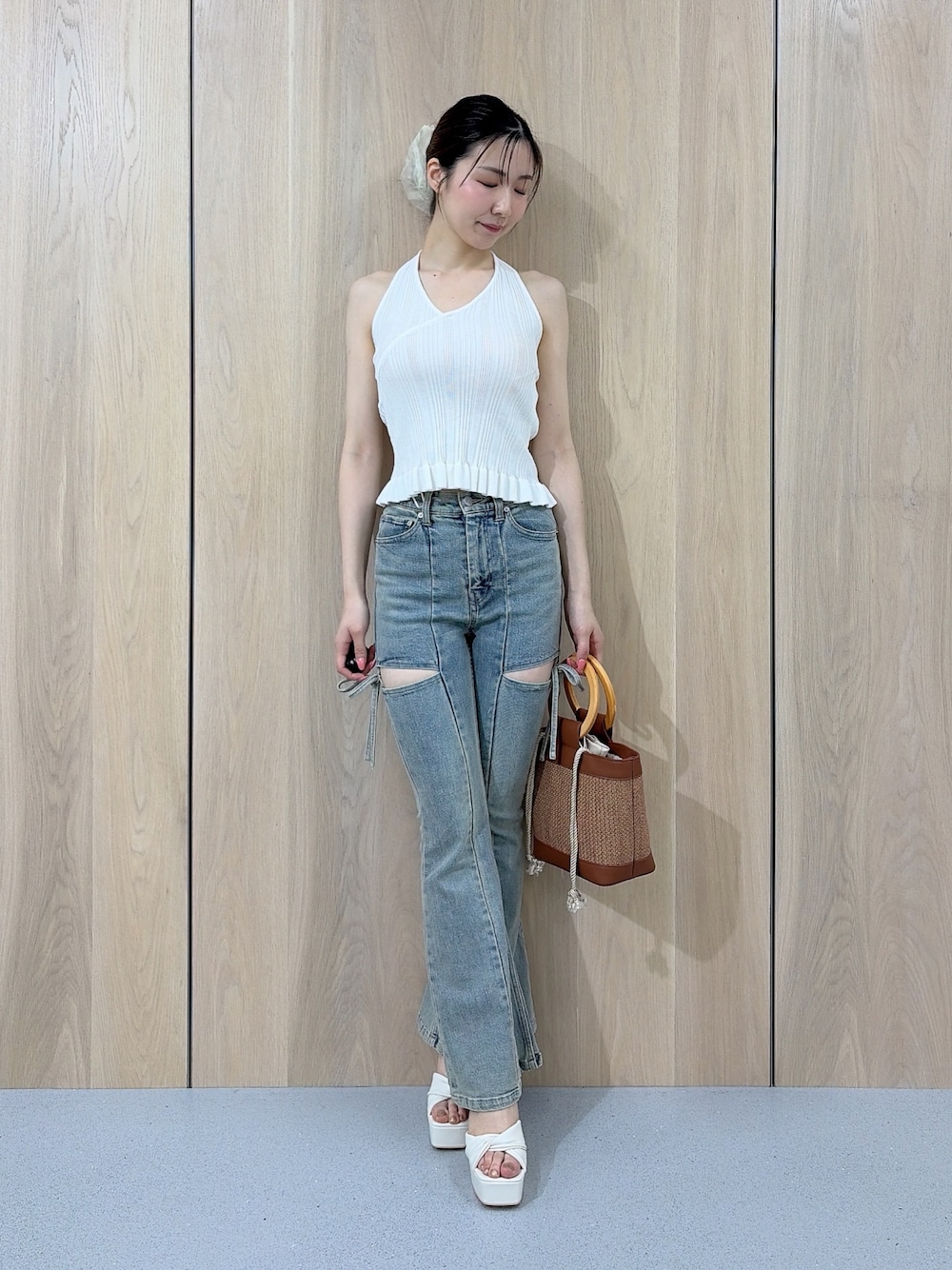 ホワイト系のニット/セーター、ブルー系のデニムパンツ、ブラウン系のハンドバッグを着用したレディースの夏コーディネートの1枚目の写真
