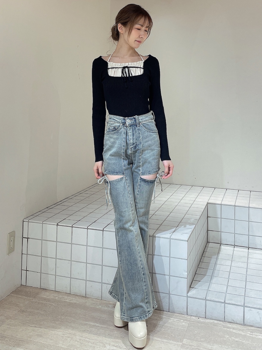 ブラック系のニット/セーター、ブルー系のデニムパンツ、ホワイト系のブーツを着用したレディースの冬コーディネートの1枚目の写真