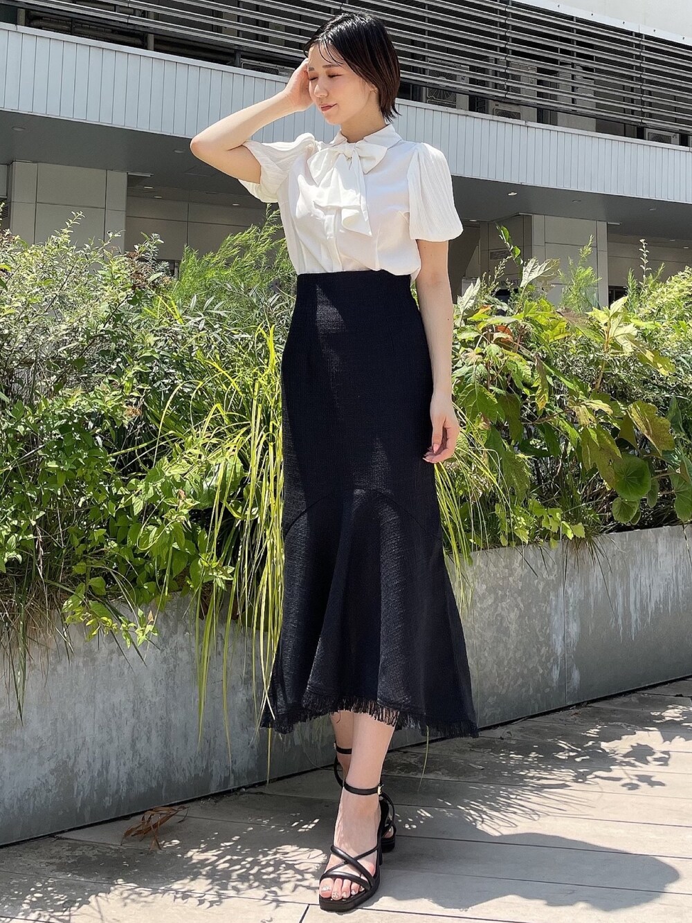 ブラック系のスカート、ホワイト系のシャツ/ブラウス、ブラック系のサンダルを着用したレディースの夏コーディネートの1枚目の写真