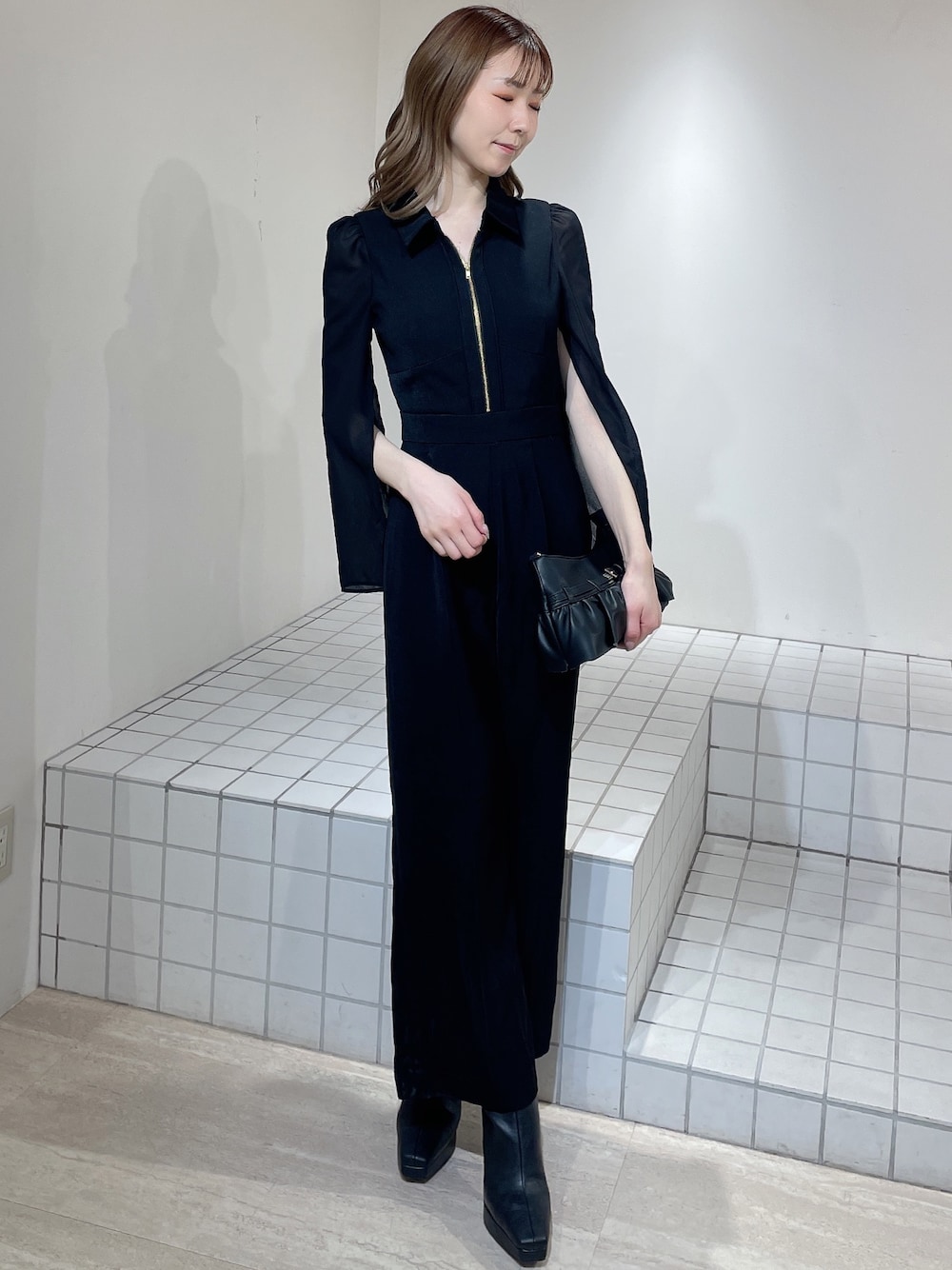 ブラック系のワンピース、ブラック系のブーツ、ブラック系のハンドバッグを着用したレディースの冬コーディネートの1枚目の写真