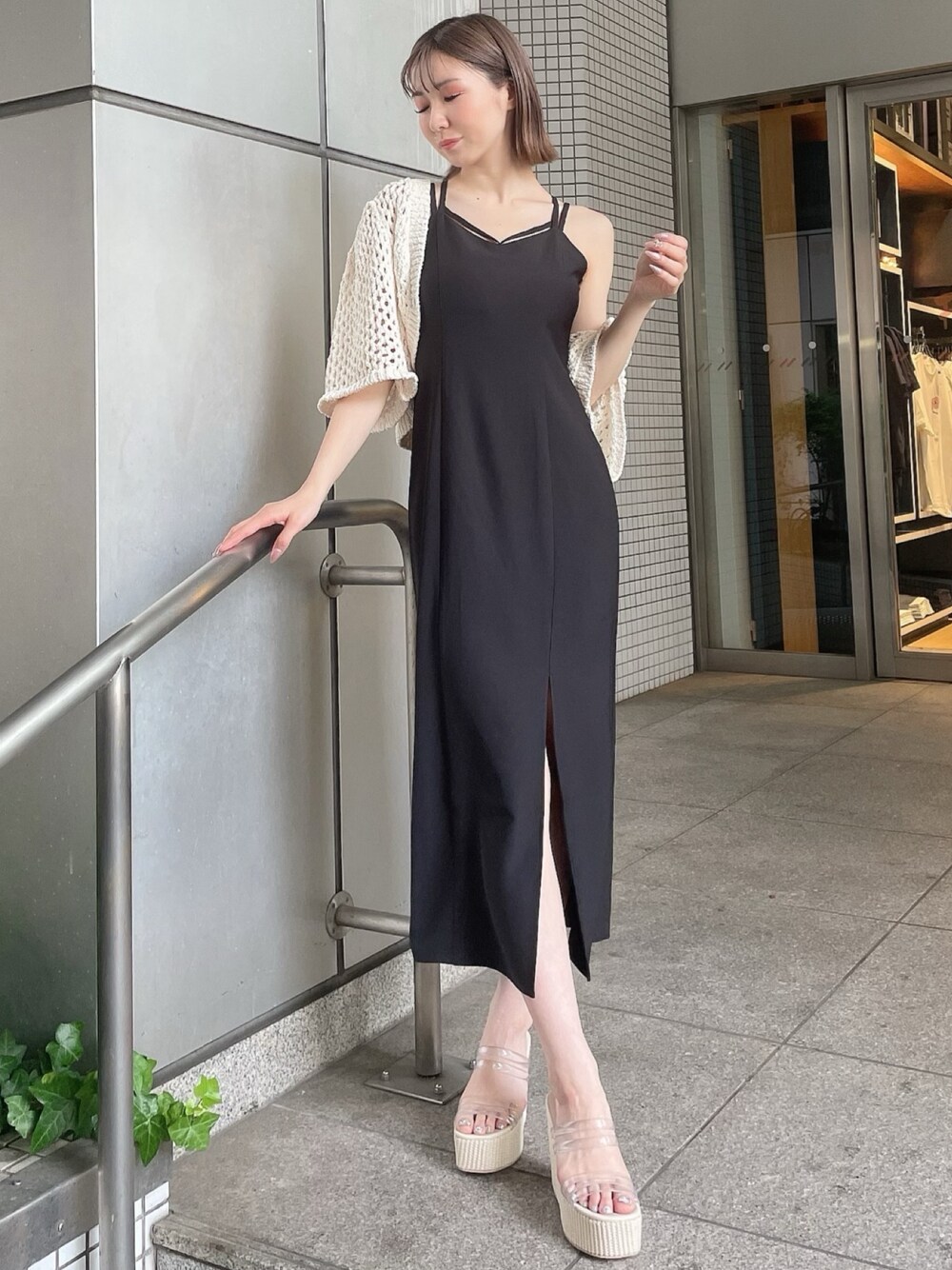 ホワイト系のカーディガン/ボレロ、ブラック系のワンピース、ホワイト系のサンダルを着用したレディースの夏コーディネートの1枚目の写真