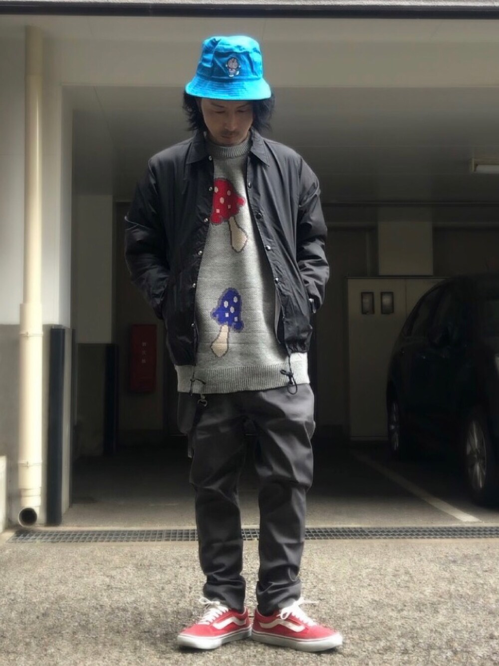 グレー系のニット/セーター、ブラック系のナイロンジャケット、レッド系のスニーカーを着用したメンズの冬コーディネートの1枚目の写真