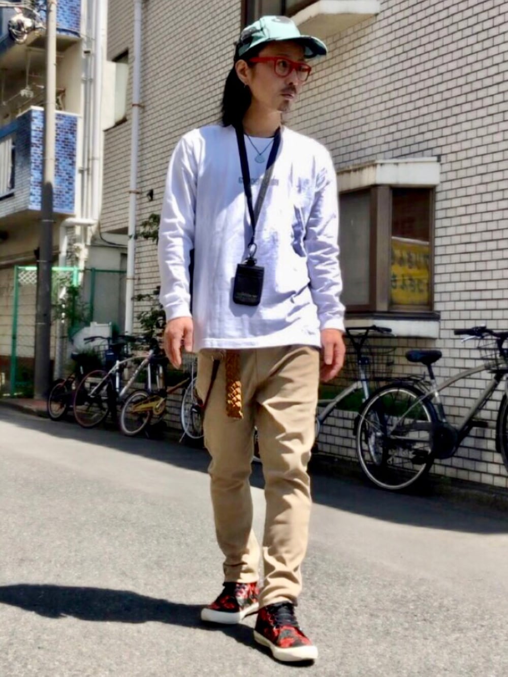 ホワイト系のTシャツ/カットソー、ベージュ系のチノパンツ、その他のスニーカーを着用したメンズの春コーディネートの1枚目の写真