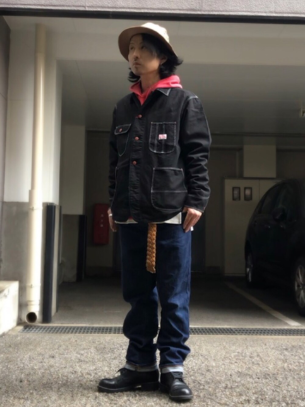 ブラック系のブーツ、ブラック系のカバーオール、ベージュ系のベルトを着用したメンズの春コーディネートの1枚目の写真