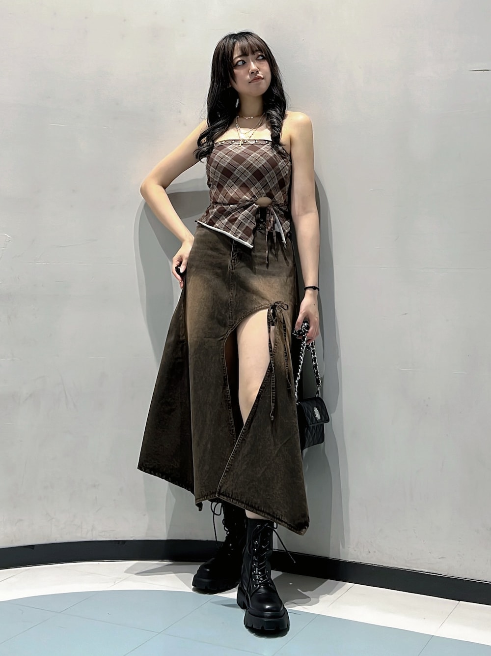 ブラウン系のキャミソール、ブラウン系のデニムスカート、ブラック系のハンドバッグを着用したレディースの秋コーディネートの1枚目の写真