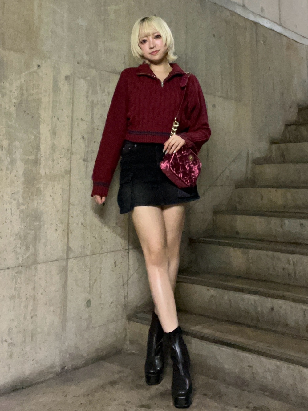 レッド系のニット/セーター、ピンク系のショルダーバッグ、ブラック系のデニムスカートを着用したレディースの秋コーディネートの1枚目の写真