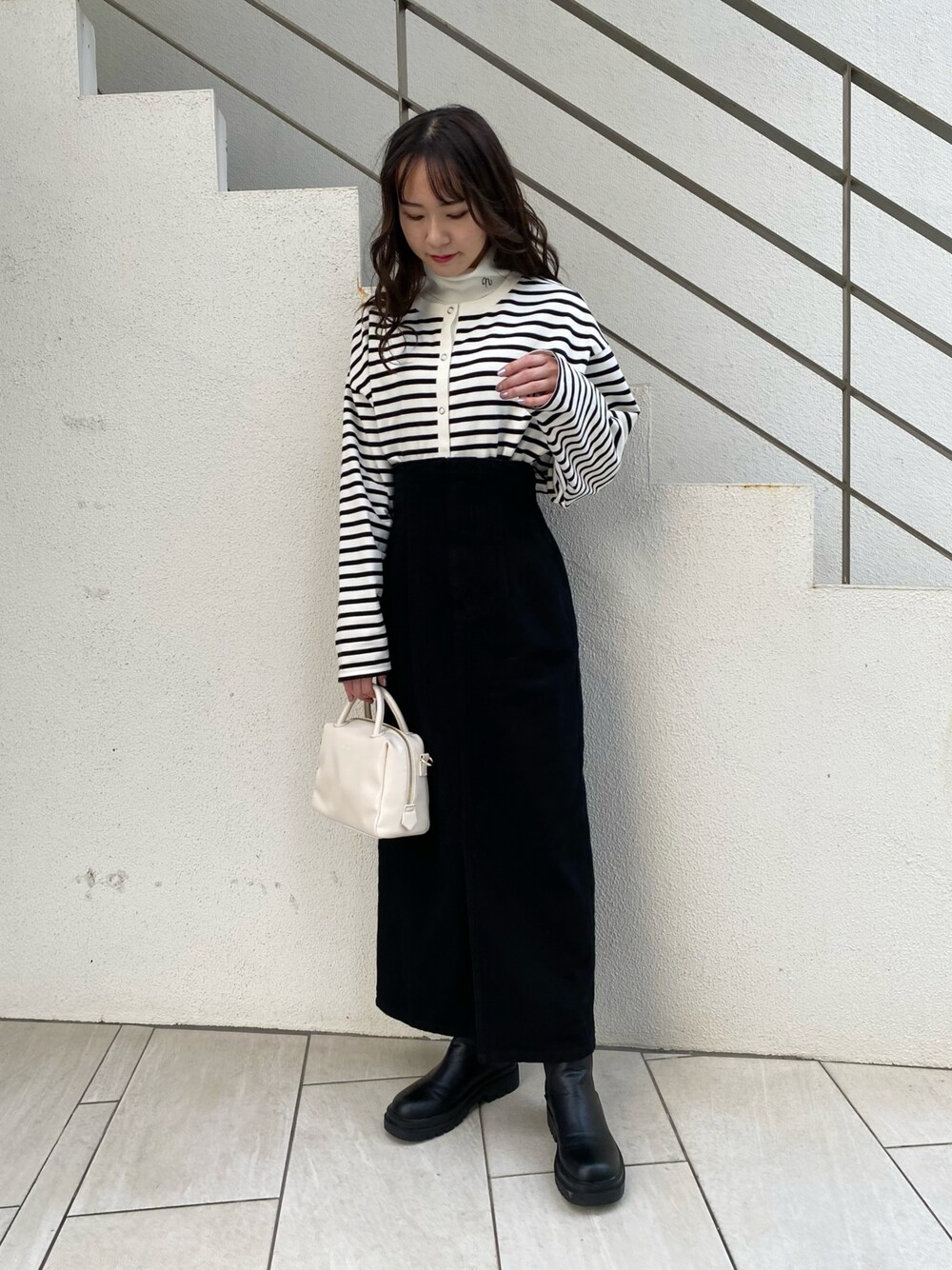 ブラック系のスカート、ブラック系のTシャツ/カットソー、ブラック系のブーツを着用したレディースの冬コーディネートの1枚目の写真