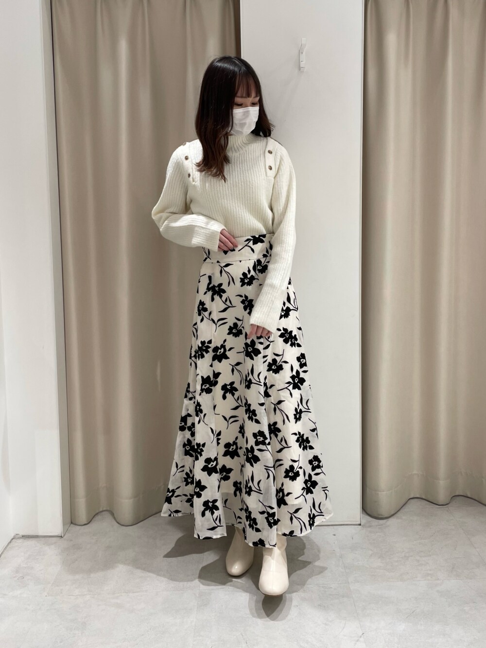 ホワイト系のニット/セーター、ホワイト系のスカート、ホワイト系のブーツを着用したレディースの秋コーディネートの1枚目の写真