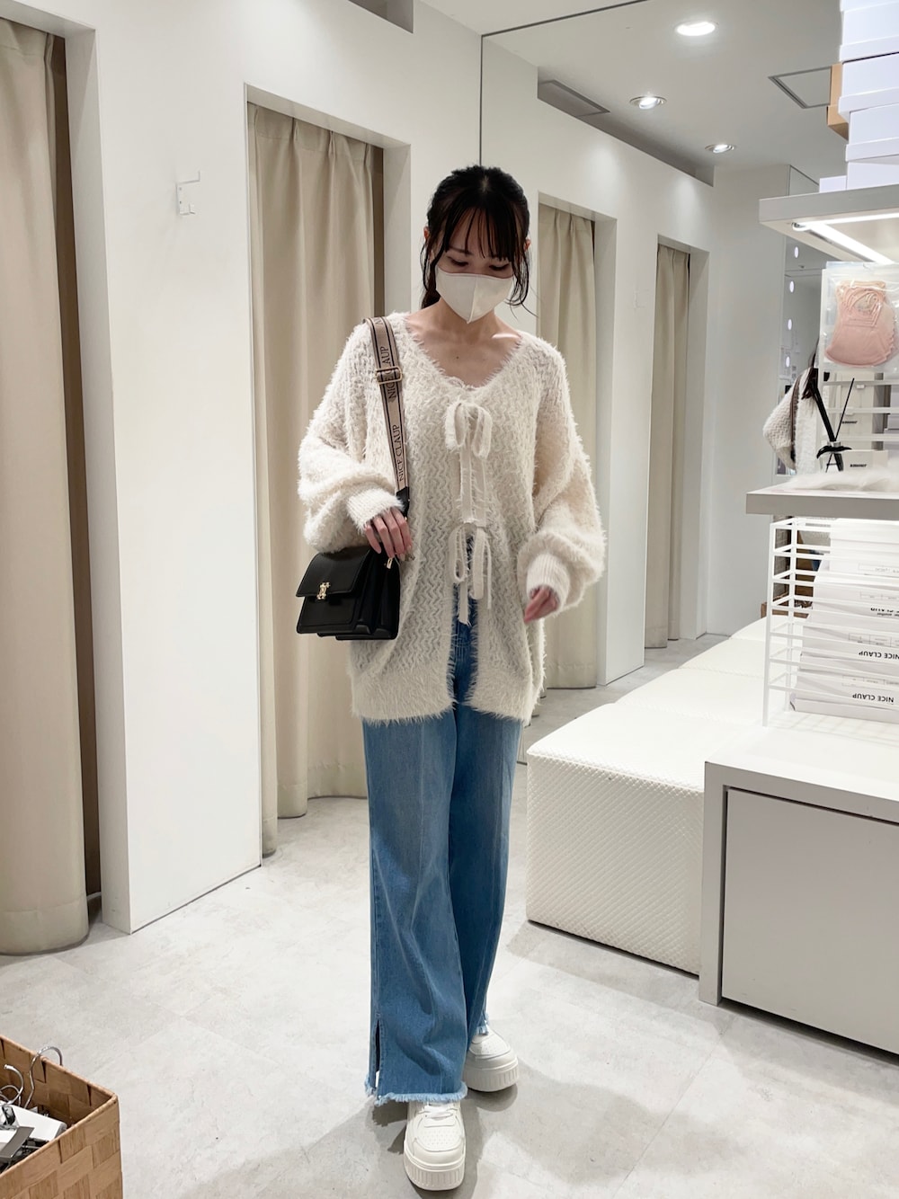 ホワイト系のカーディガン/ボレロ、ブルー系のデニムパンツ、ブラック系のショルダーバッグを着用したレディースの秋コーディネートの1枚目の写真