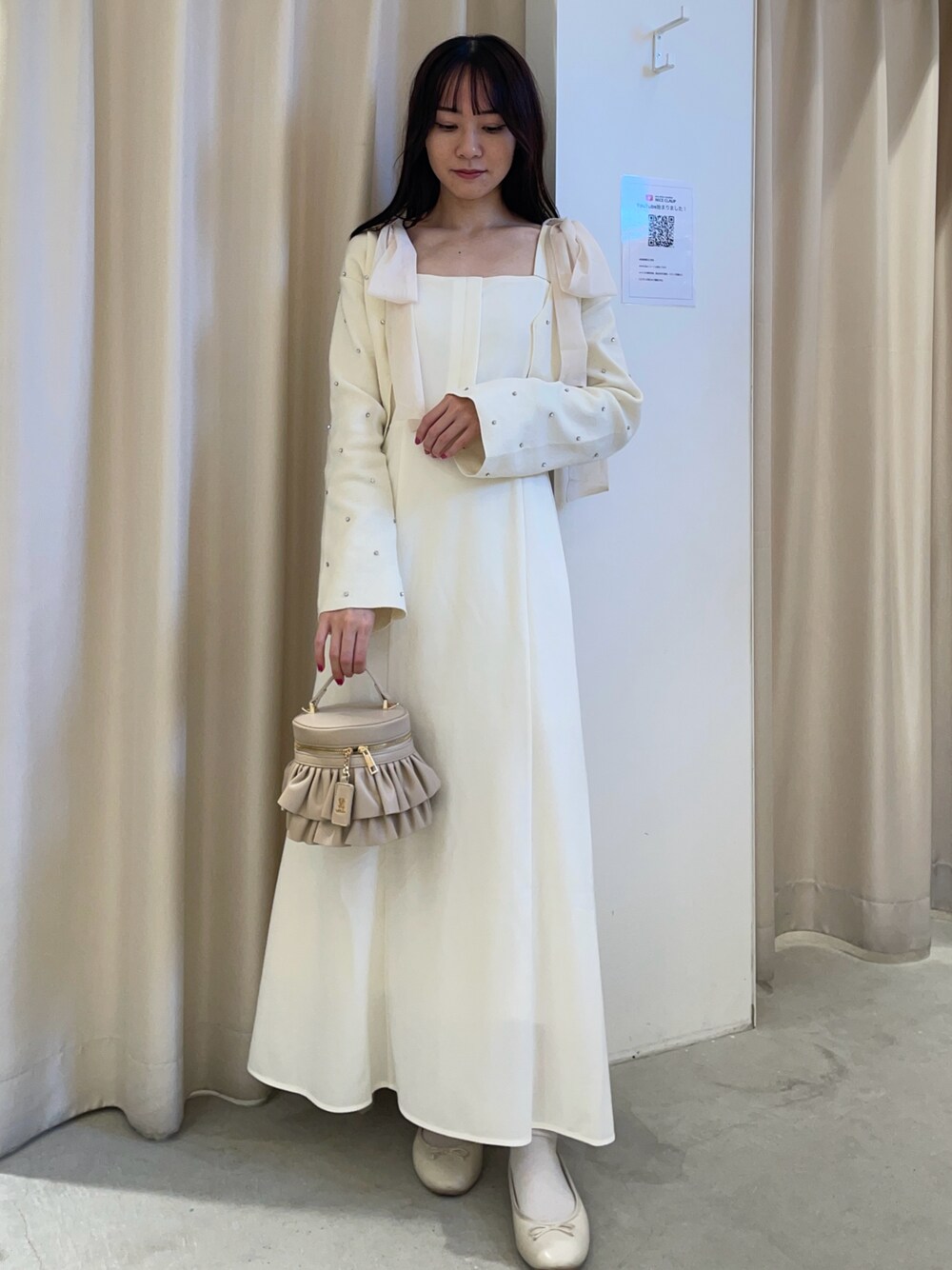 ホワイト系のカーディガン/ボレロ、ホワイト系のワンピース、ベージュ系のショルダーバッグを着用したレディースの秋コーディネートの1枚目の写真