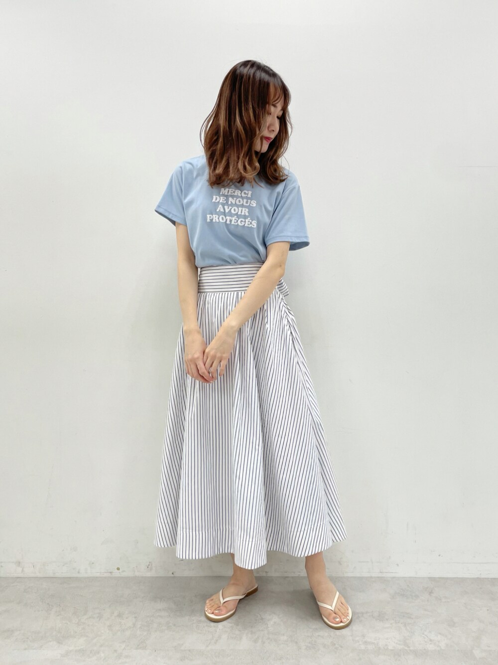 ブルー系のスカート、ブルー系のTシャツ/カットソー、ホワイト系のサンダルを着用したレディースの夏コーディネートの1枚目の写真