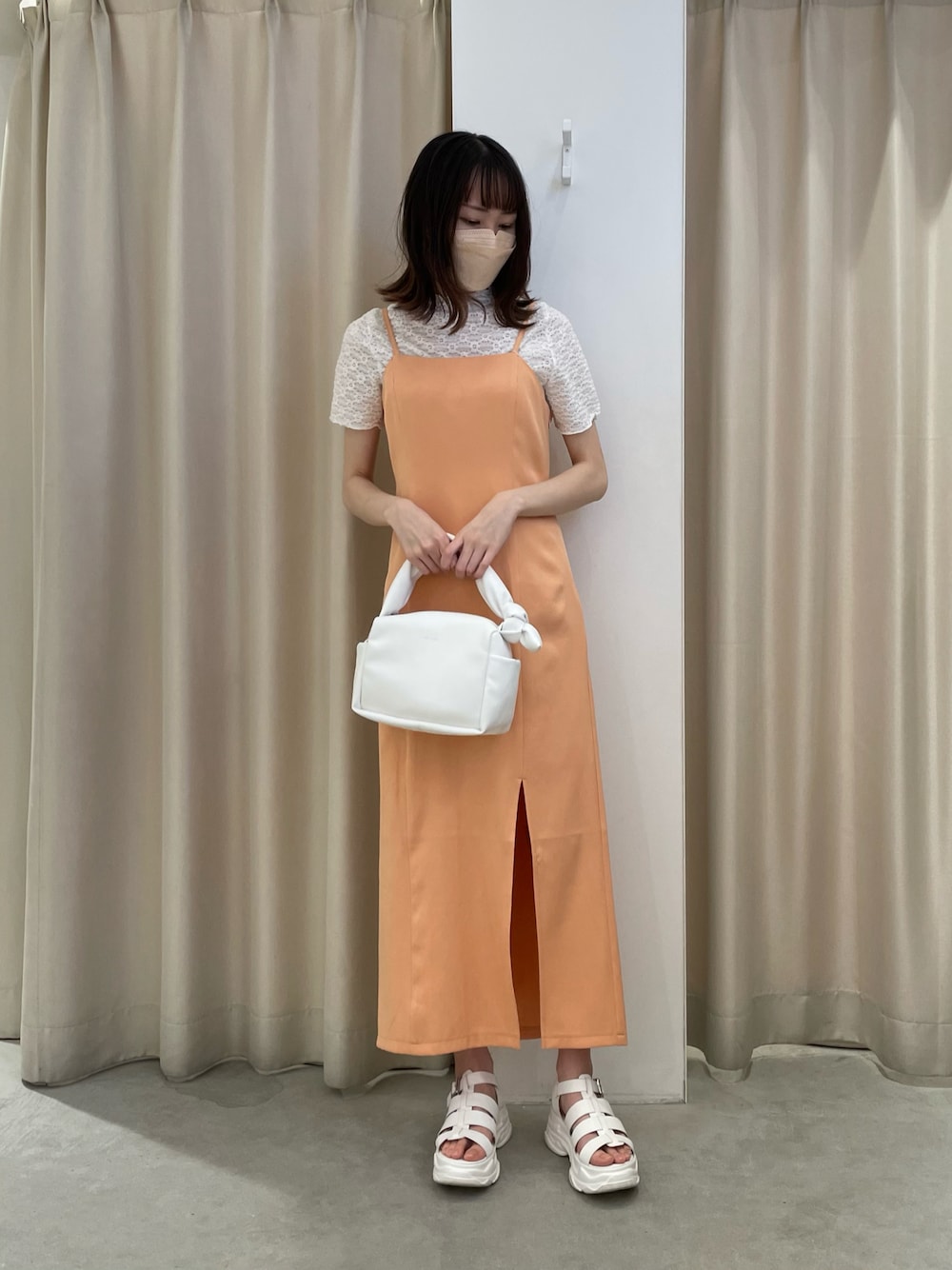 オレンジ系のワンピース、ホワイト系のTシャツ/カットソー、ホワイト系のハンドバッグを着用したレディースの夏コーディネートの1枚目の写真