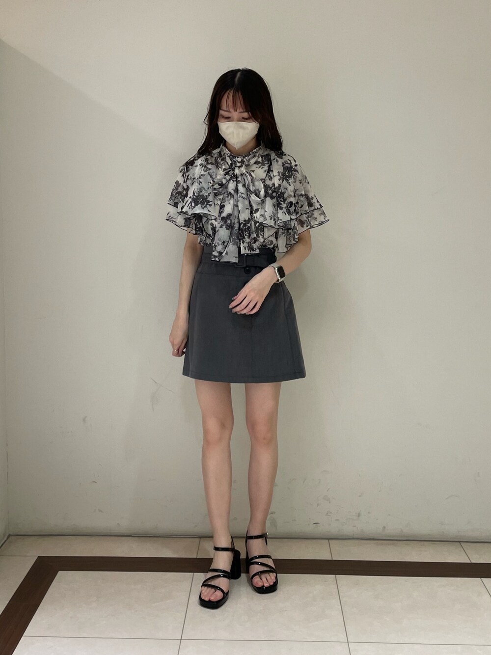 ホワイト系のシャツ/ブラウス、グレー系のスカート、ブラック系のサンダルを着用したレディースの夏コーディネートの1枚目の写真