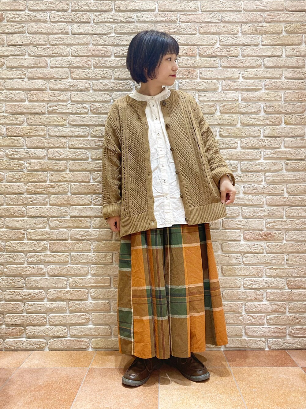 オレンジ系のスカート、ホワイト系のシャツ/ブラウス、ベージュ系のニット/セーターを着用したレディースの秋コーディネートの1枚目の写真