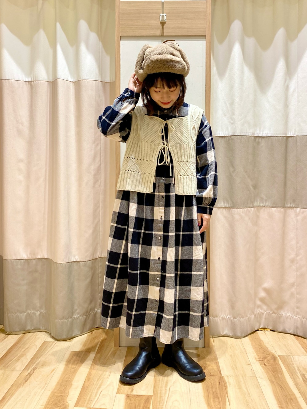 ブラック系のワンピース、ホワイト系のベスト、ブラック系のブーツを着用したレディースの冬コーディネートの1枚目の写真