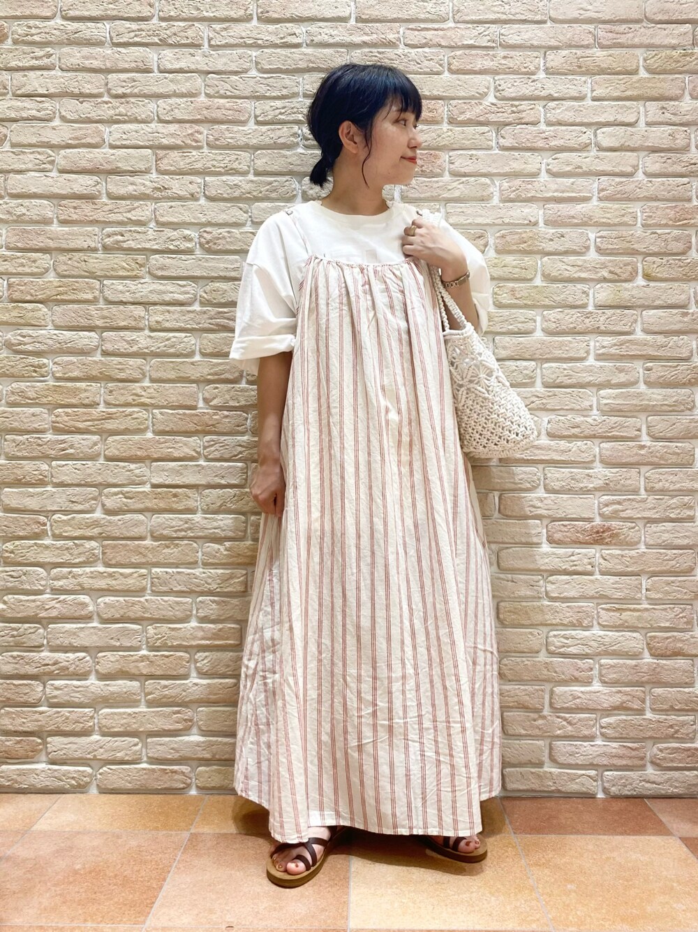 ブラウン系のシューズ、レッド系のワンピース、ホワイト系のTシャツ/カットソーを着用したレディースの春コーディネートの1枚目の写真