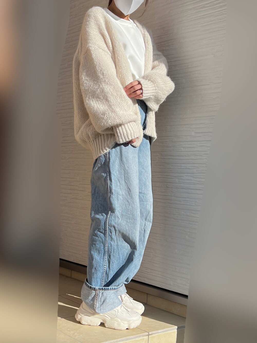 ホワイト系のカーディガン/ボレロ、ブルー系のデニムパンツ、ベージュ系のスニーカーを着用したレディースの秋コーディネートの1枚目の写真