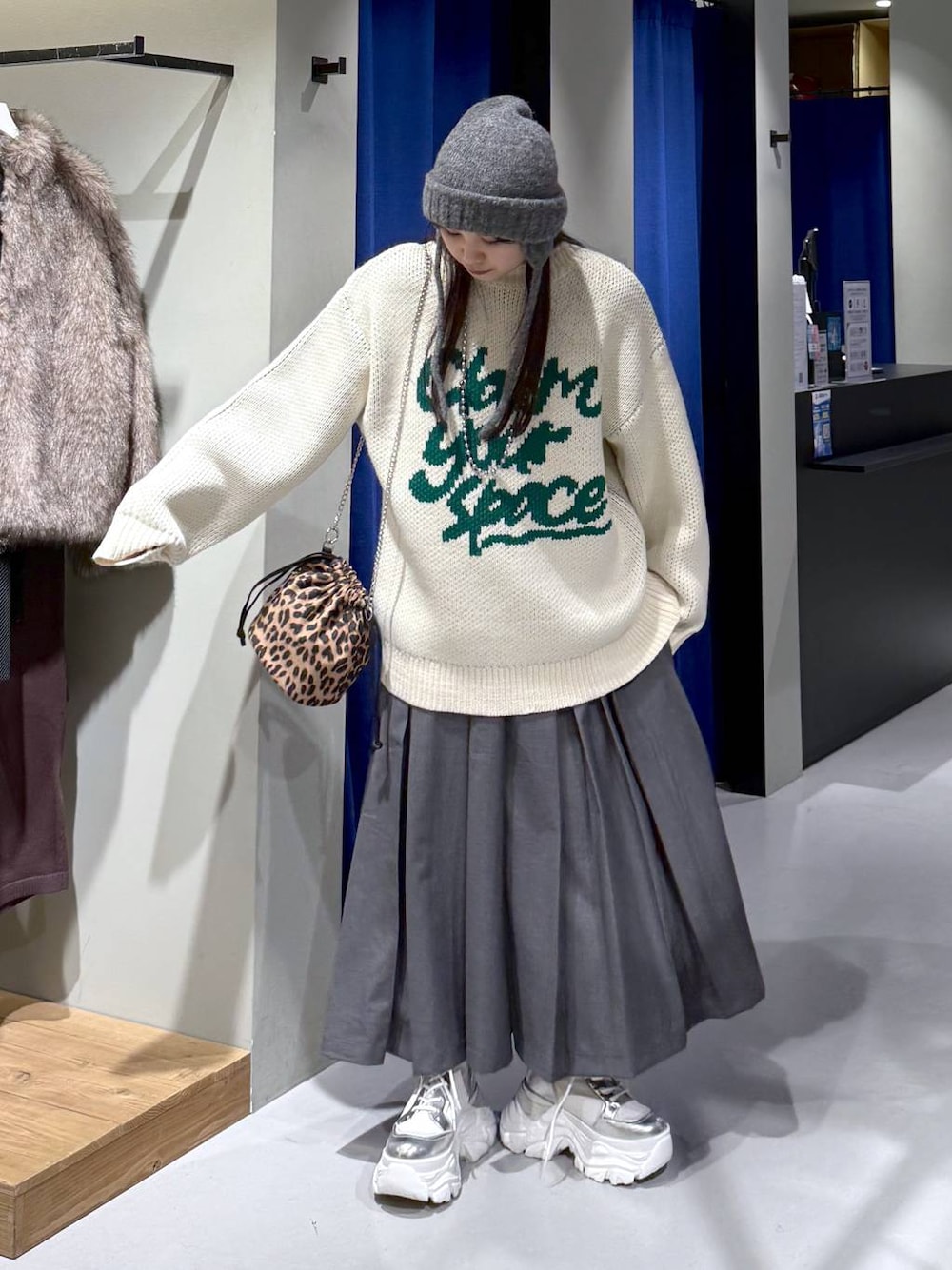 ホワイト系のブーツ、ホワイト系のニット/セーター、グレー系のスカートを着用したレディースの冬コーディネートの1枚目の写真