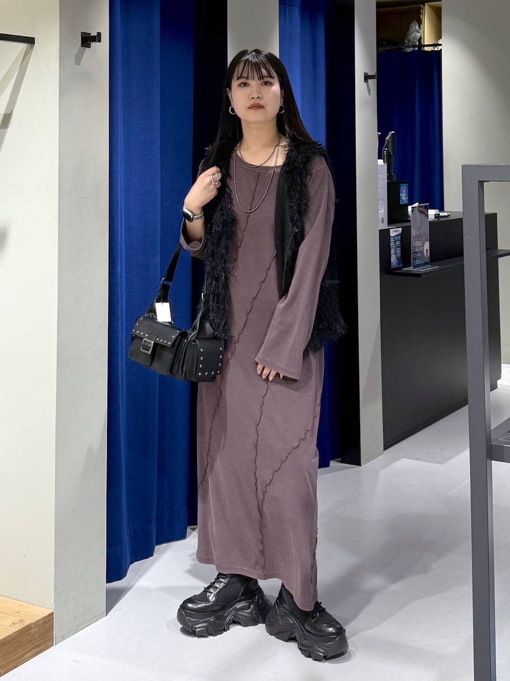 ブラック系のブーツ、ブラック系のショルダーバッグ、ブラック系のベストを着用したレディースの秋コーディネートの1枚目の写真