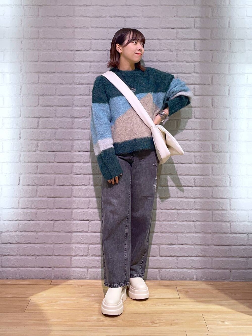 ブラック系のデニムパンツ、ホワイト系のブーツ、ホワイト系のショルダーバッグを着用したレディースの秋コーディネートの1枚目の写真
