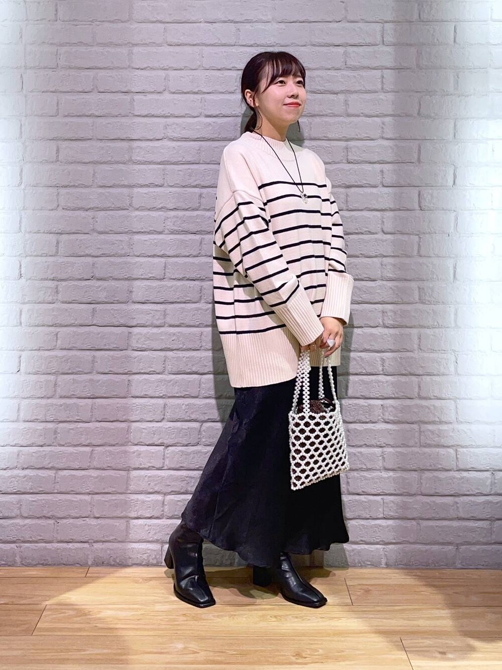 その他のニット/セーター、ブラック系のパンプス、ホワイト系のショルダーバッグを着用したレディースの秋コーディネートの1枚目の写真