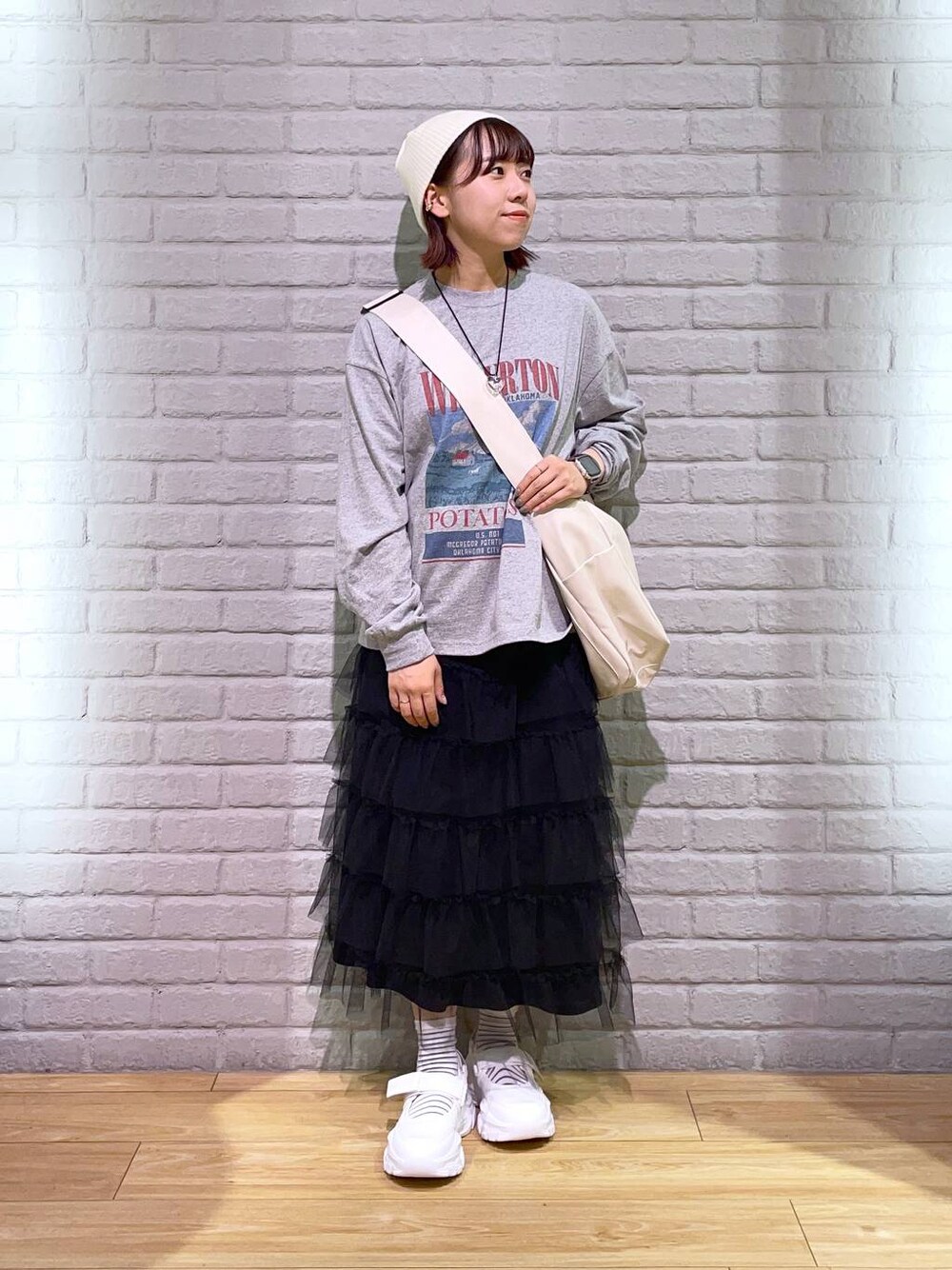 ホワイト系のボディバッグ/ウエストポーチ、グレー系のTシャツ/カットソー、ブラック系のスカートを着用したレディースの秋コーディネートの1枚目の写真