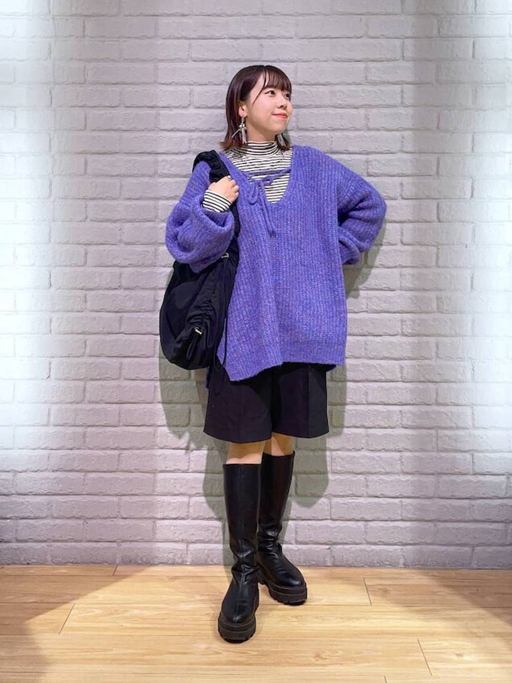 ホワイト系のTシャツ/カットソー、パープル系のニット/セーター、ブラック系のブーツを着用したレディースの秋コーディネートの1枚目の写真