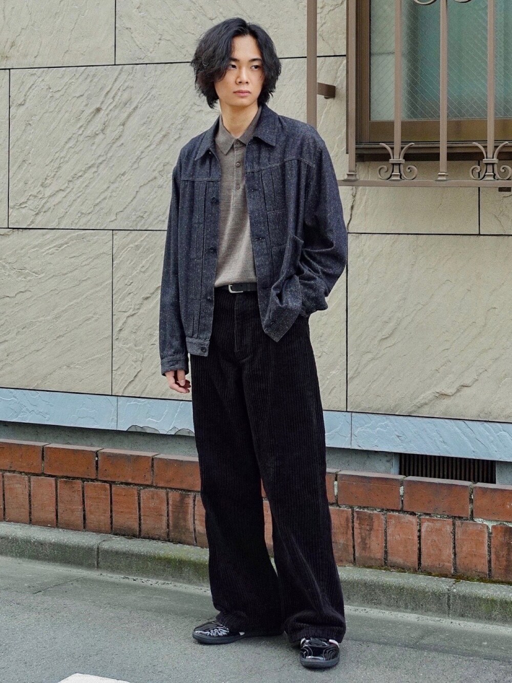 ブラック系のデニムジャケット、ブラック系のスニーカー、ブラウン系のポロシャツを着用したメンズの秋コーディネートの1枚目の写真
