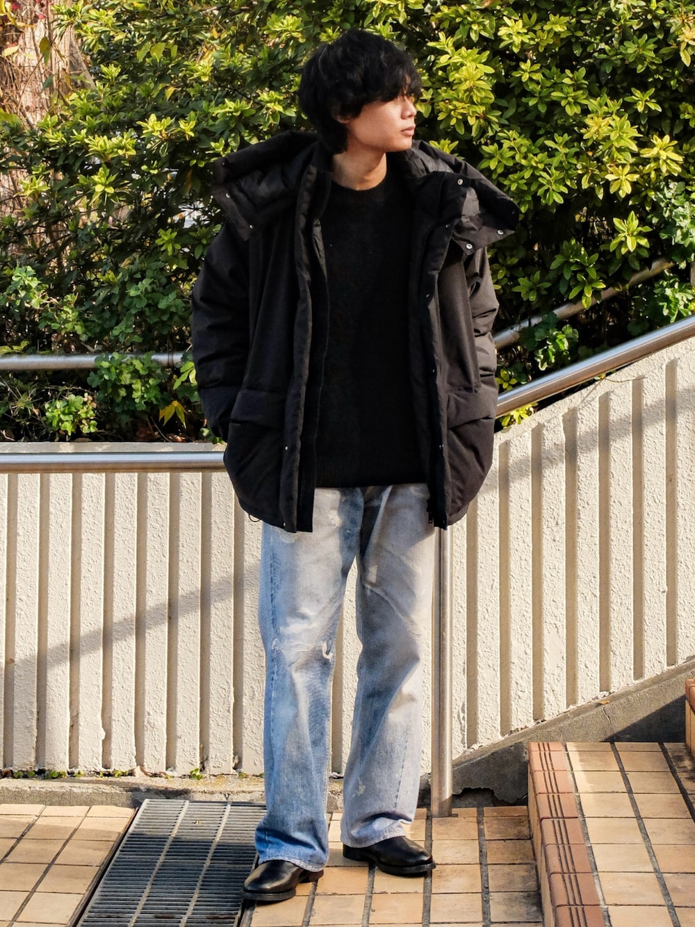 ブラック系のニット/セーター、ブラック系のダウンジャケット/コート、ブルー系のデニムパンツを着用したメンズの冬コーディネートの1枚目の写真