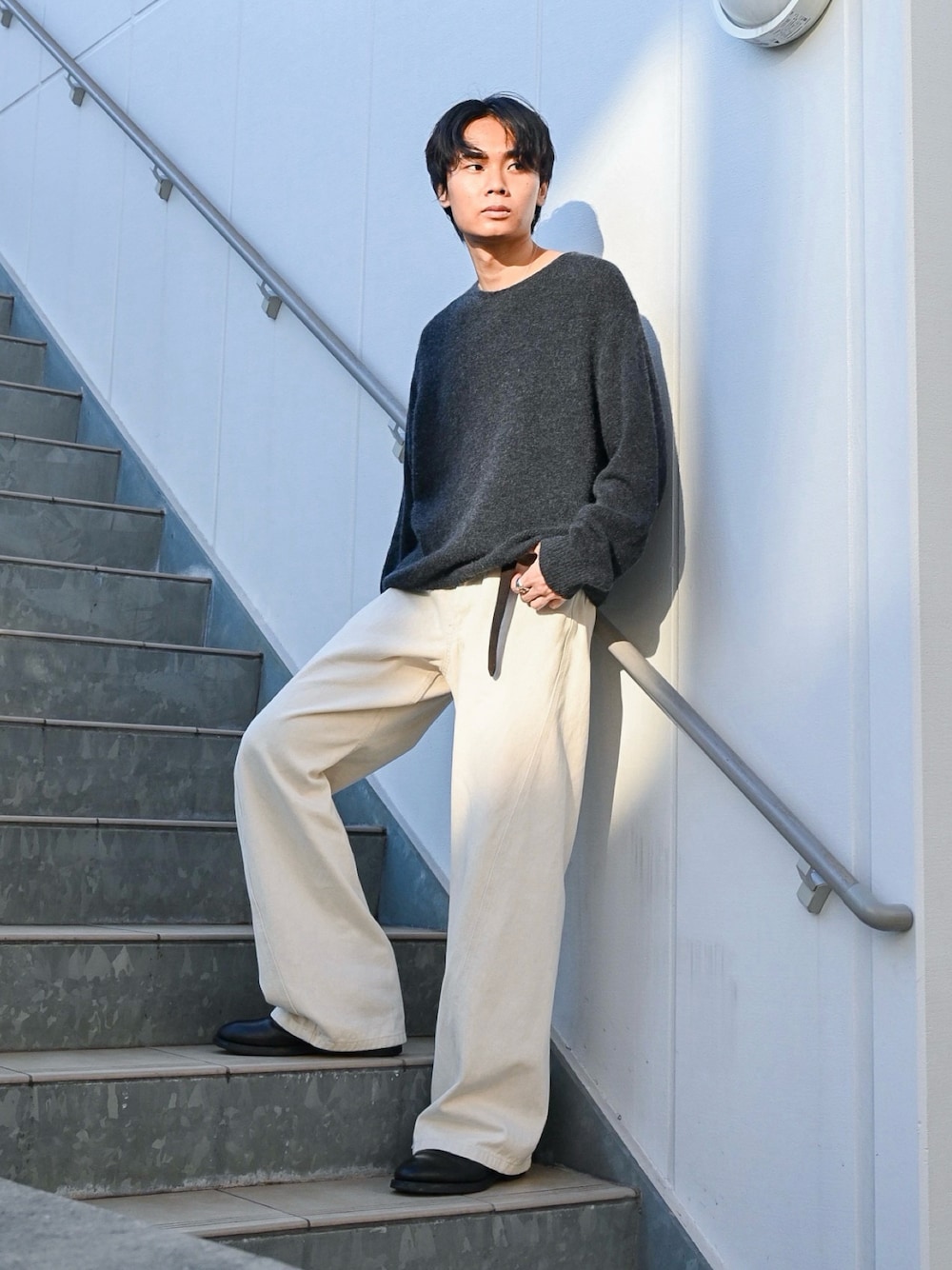 ブラック系のブーツ、ホワイト系のデニムパンツ、ブラック系のニット/セーターを着用したメンズの秋コーディネートの1枚目の写真