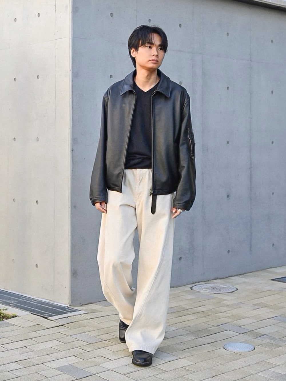 ホワイト系のデニムパンツ、ブラック系のドレスシューズ、ブラック系のブルゾンを着用したメンズの秋コーディネートの1枚目の写真