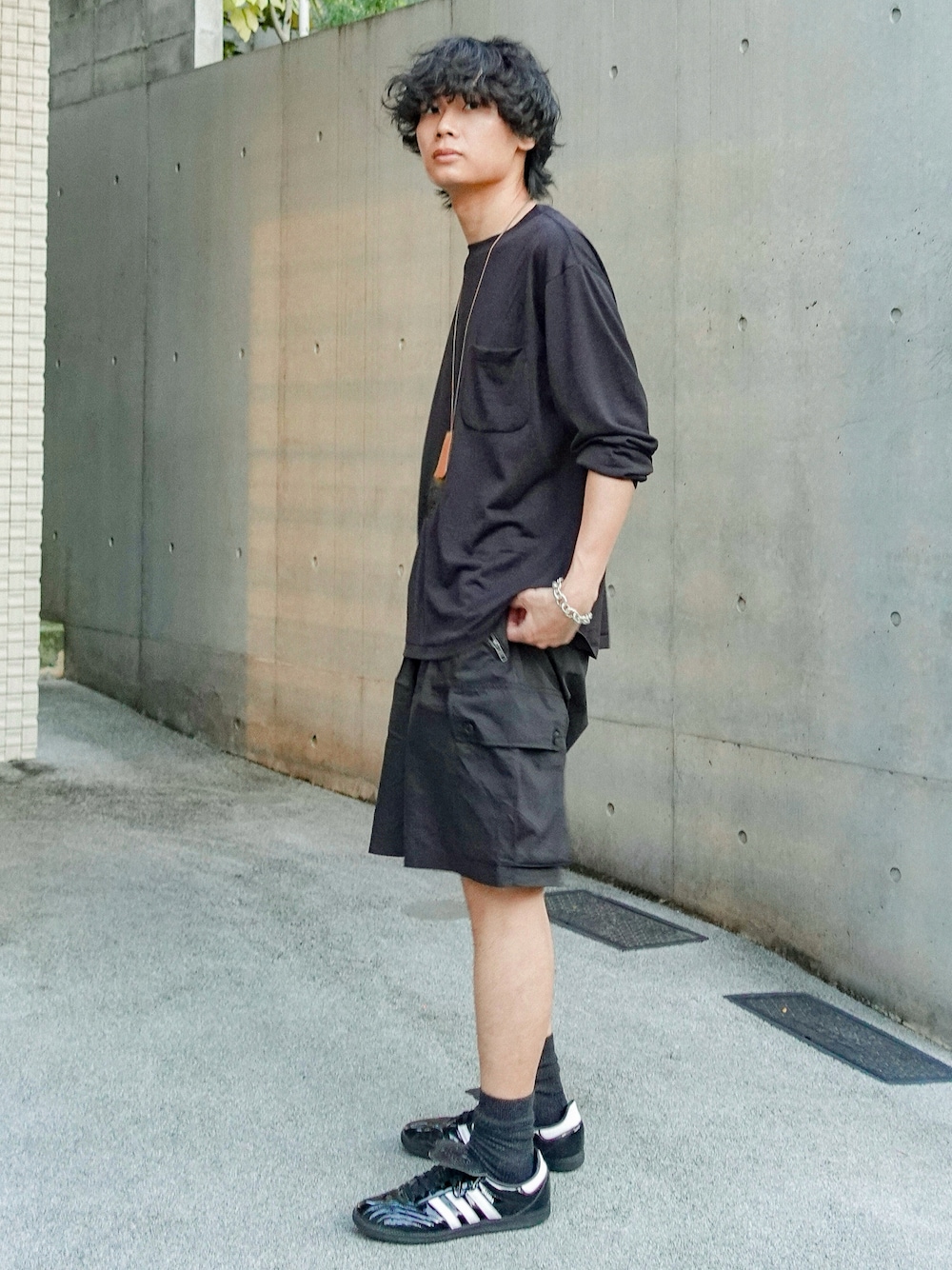 ブラック系のスニーカー、ブラック系のTシャツ/カットソー、ブラック系のカーゴパンツを着用したメンズの夏コーディネートの1枚目の写真