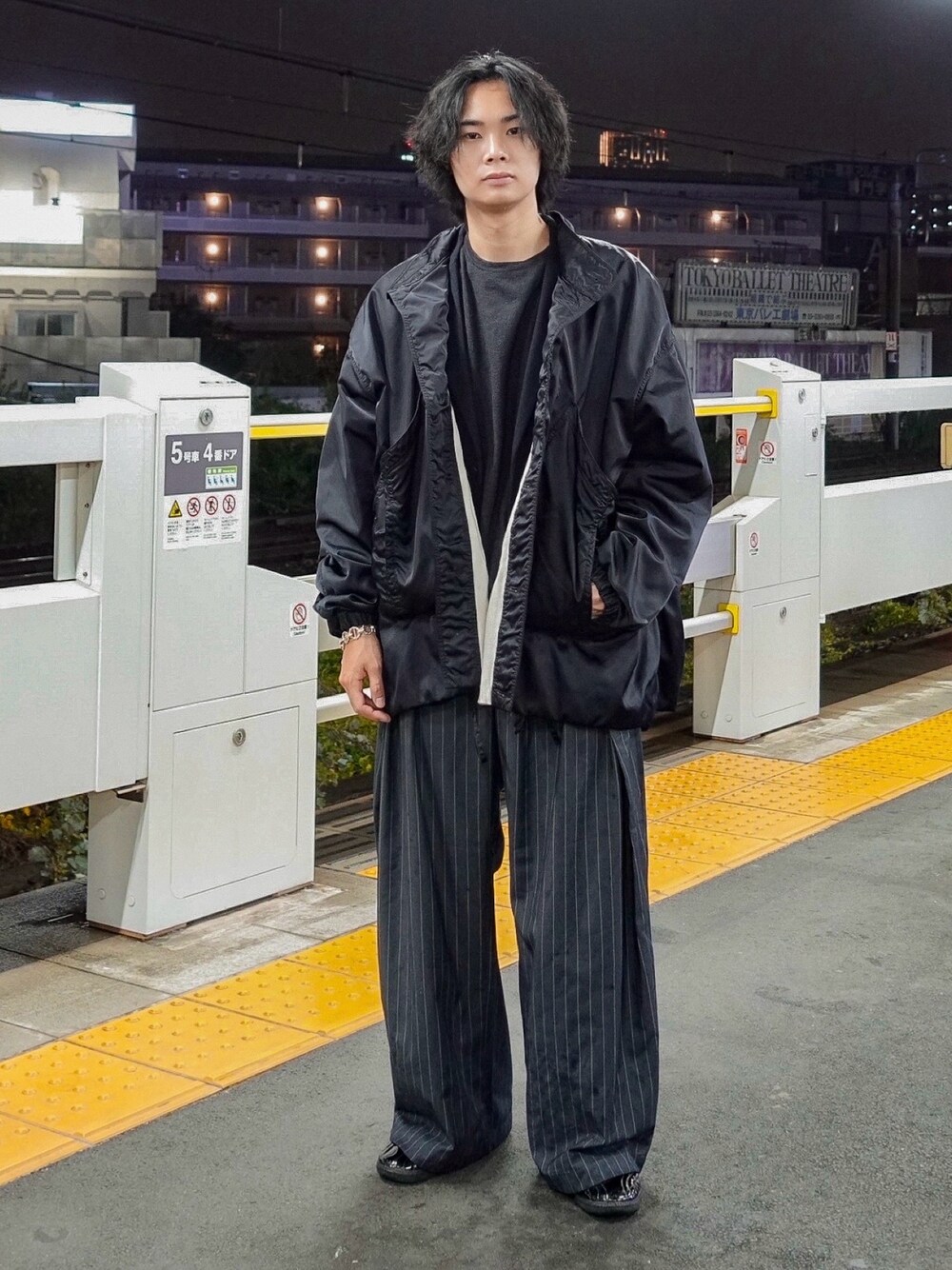 グレー系のスラックス、グレー系のTシャツ/カットソー、ブラック系のスニーカーを着用したメンズの秋コーディネートの1枚目の写真