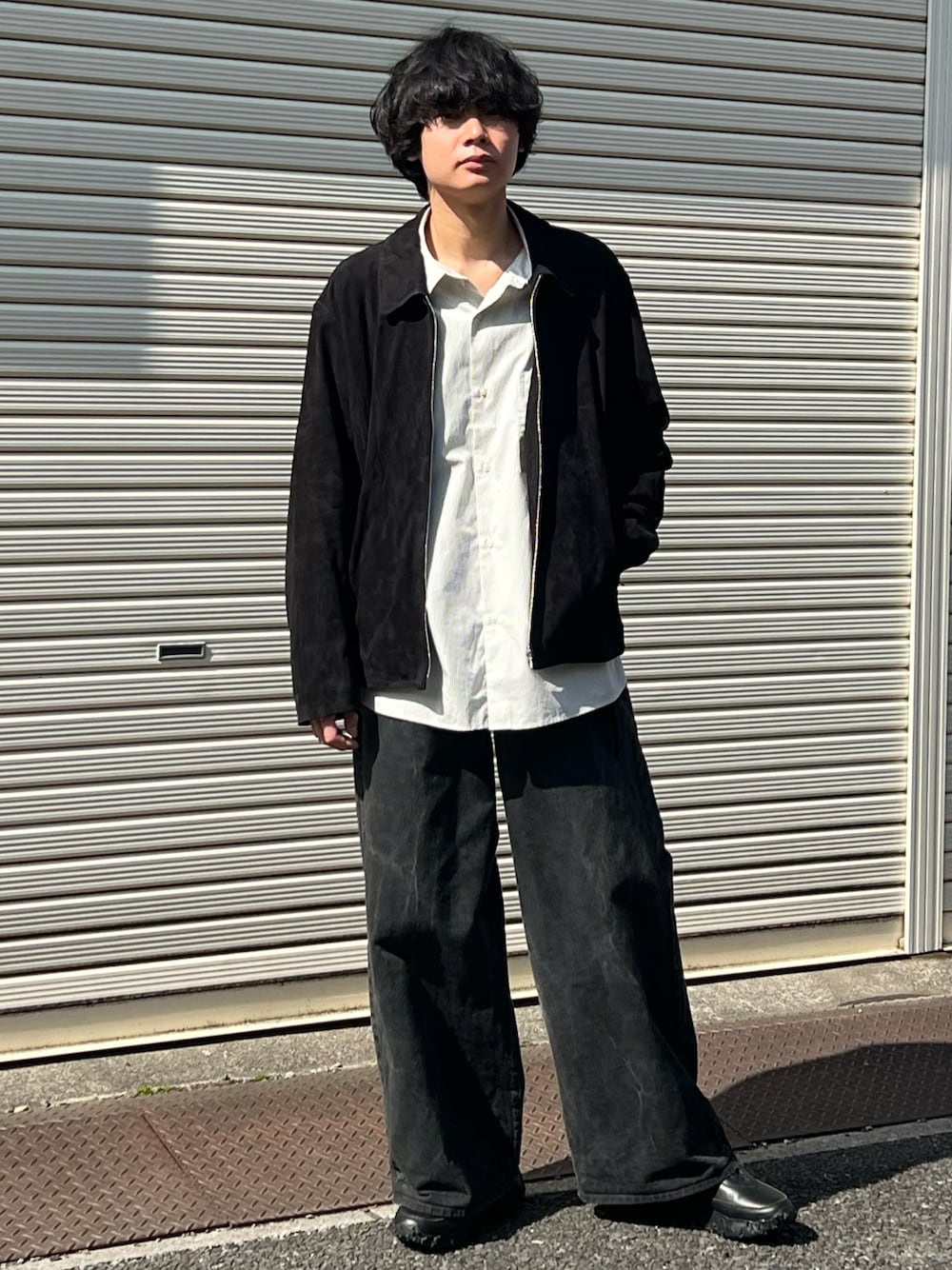 ブラック系のデニムパンツ、ブラック系のスニーカー、ブラック系のブルゾンを着用したメンズの春コーディネートの1枚目の写真