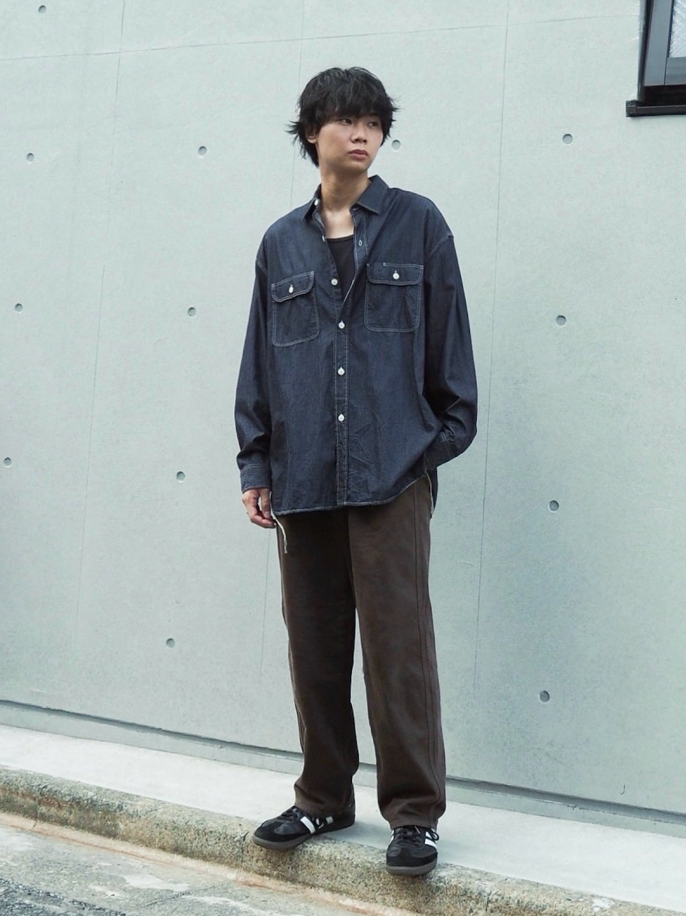 ブラウン系のデニムパンツ、ブルー系のシャツ/ブラウス、ブラック系のスニーカーを着用したメンズの秋コーディネートの1枚目の写真