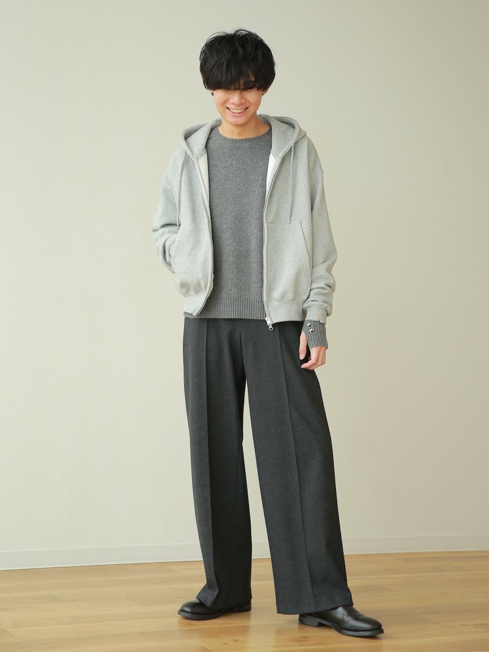 グレー系のパーカー、グレー系のニット/セーター、グレー系のスラックスを着用したメンズの秋コーディネートの1枚目の写真