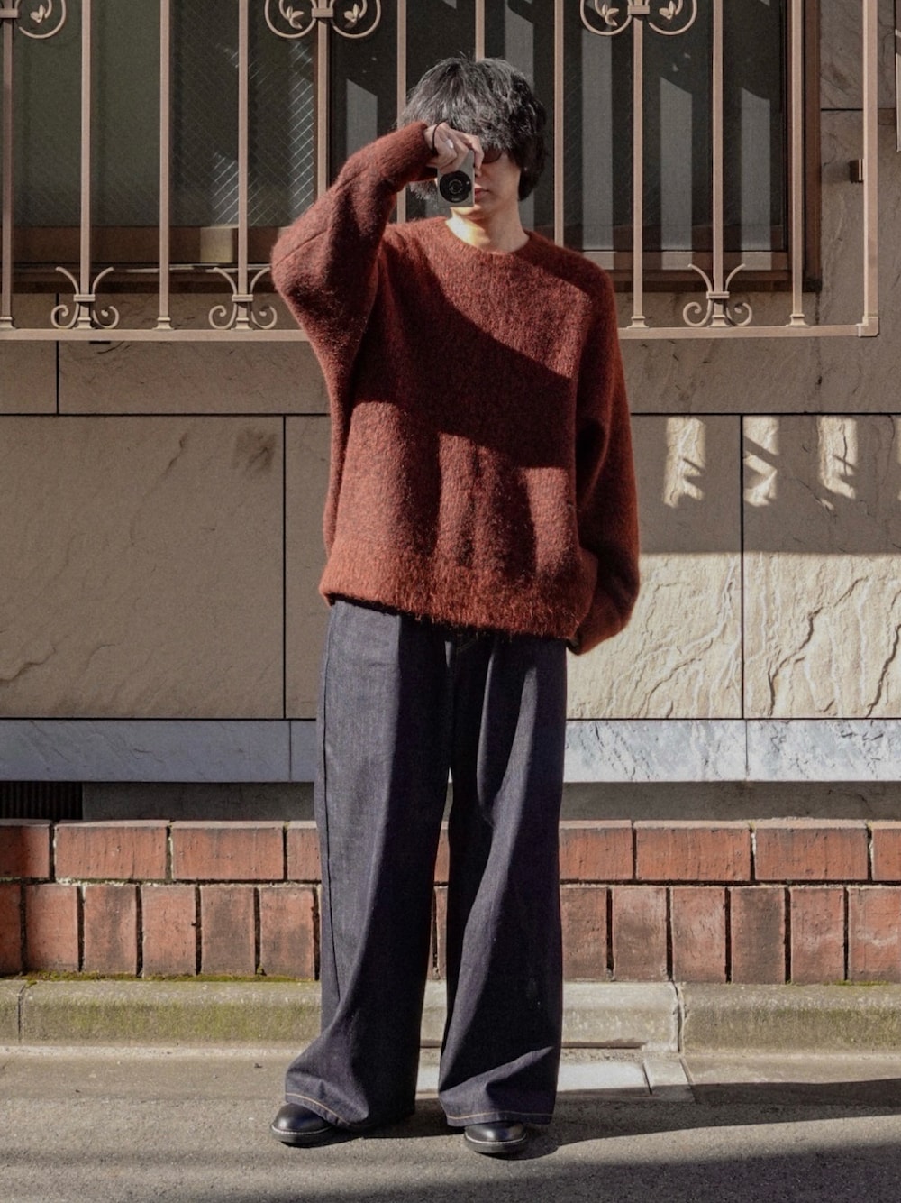 ブルー系のデニムパンツ、ブラック系のドレスシューズ、ブラウン系のニット/セーターを着用したメンズの冬コーディネートの1枚目の写真