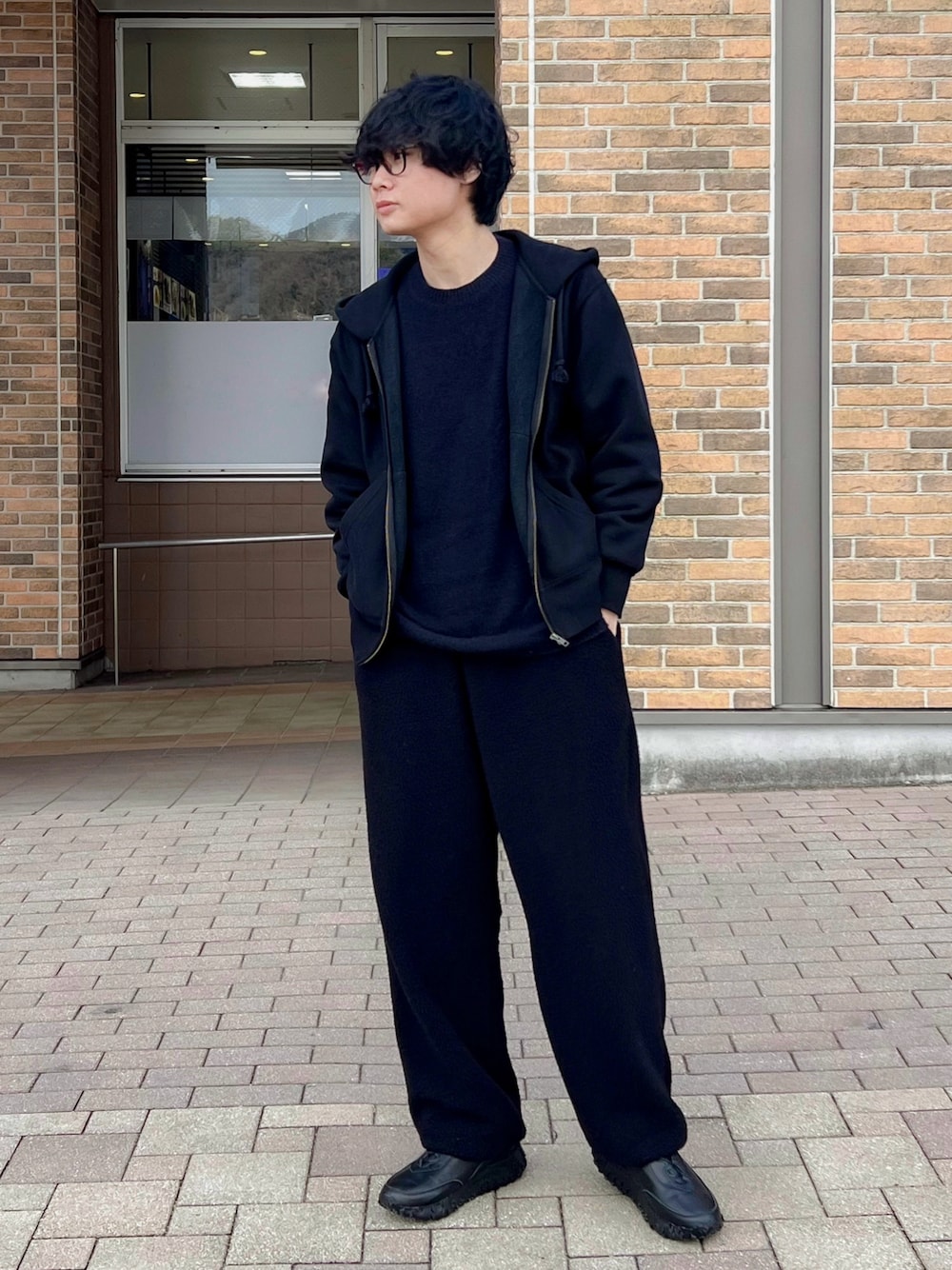 ブルー系のパンツ、ブルー系のニット/セーター、ブラック系のパーカーを着用したメンズの冬コーディネートの1枚目の写真