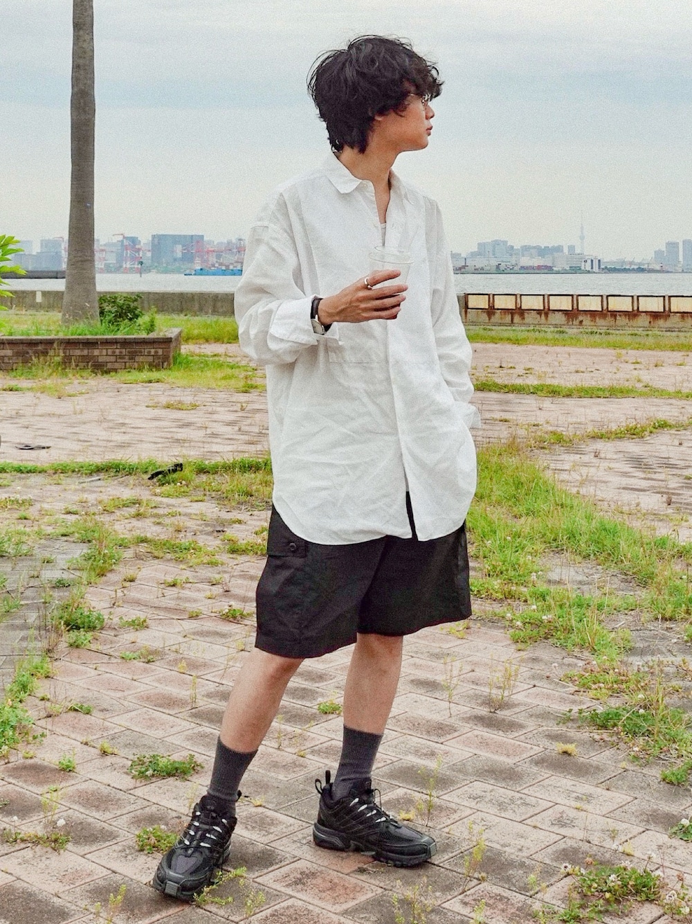 ブラック系のスニーカー、ホワイト系のシャツ/ブラウス、ブラック系のカーゴパンツを着用したメンズの夏コーディネートの1枚目の写真